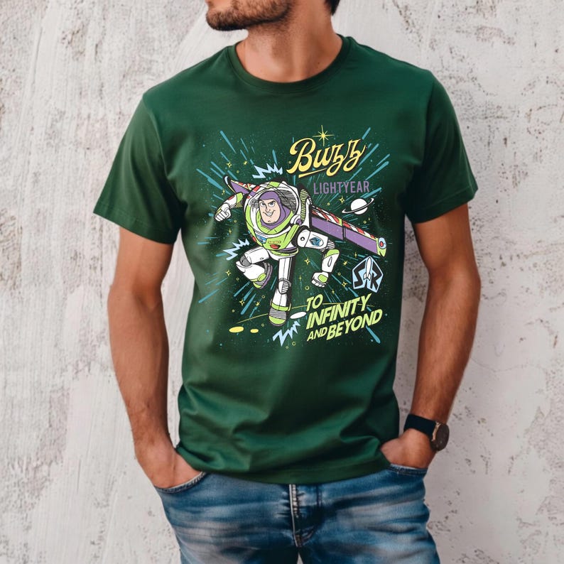 May include: Green t-shirt featuring a graphic of Buzz Lightyear from Toy Story. The design includes the text "Buzz Lightyear" and "To Infinity and Beyond" in a colorful, cartoon style. The shirt is short-sleeved.