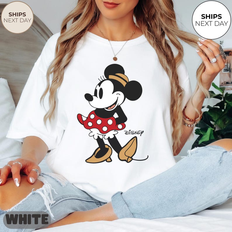 Puede incluir: Camiseta blanca con un gr&aacute;fico de Minnie Mouse. El personaje de dibujos animados est&aacute; representado en negro, rojo y amarillo, con la palabra "Disney" impresa debajo. La camiseta tiene un corte holgado.