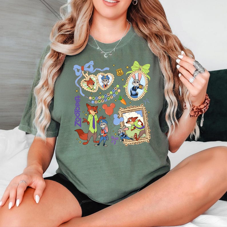Może przedstawiać: Zielona koszulka w kolorze oliwkowym z kolorowymi ilustracjami postaci z filmu Zootopia. Projekt zawiera oprawione portrety, napis "Zootopia" i kultowe uszy Myszki Miki. Koszulka wykonana jest z miękkiego materiału.