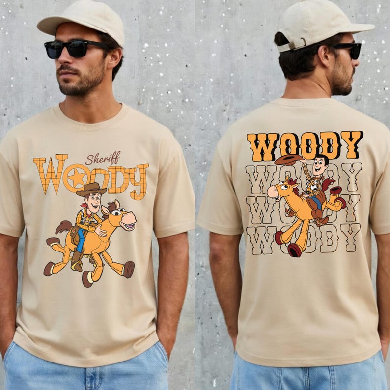 May include: Beige t-shirt featuring a cartoon illustration of Woody riding a horse, with the word "Woody" in a western-style font. The front of the shirt has the text "Sheriff Woody". The back of the shirt repeats the Woody graphic.