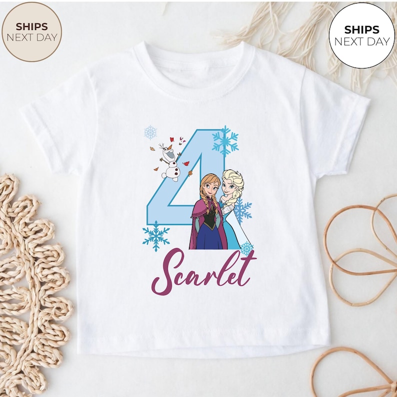 May include: White t-shirt with a blue number 4 design, snowflakes, and characters Anna, Elsa, and Olaf from Frozen. The name "Scarlet" is written in a cursive font. The shirt has short sleeves.