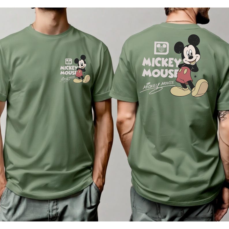 May include: Olive green t-shirt featuring Mickey Mouse. The front has a small graphic of Mickey Mouse with the words "Mickey Mouse". The back has a larger Mickey Mouse graphic and the words "Mickey Mouse".
