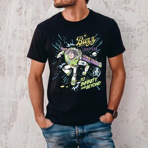 May include: Black t-shirt featuring a graphic of Buzz Lightyear from Toy Story. The design includes the text "Buzz Lightyear" and "To Infinity and Beyond" in a colorful, cartoon style. The character is depicted in his space suit.