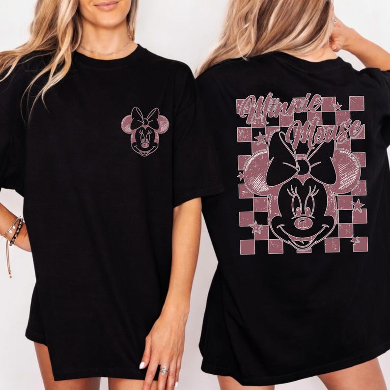 May include: Black t-shirts featuring a Minnie Mouse graphic. The front of the shirt has a small Minnie Mouse design, while the back showcases a larger design with the words "Minnie Mouse" and a checkered pattern.