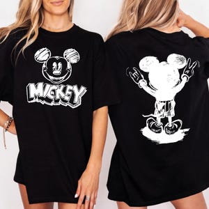 May include: Black t-shirts with a white Mickey Mouse graphic. One shirt features Mickey's face with the word "Mickey" below. The other shirt shows Mickey with his arms up in a rock and roll pose.