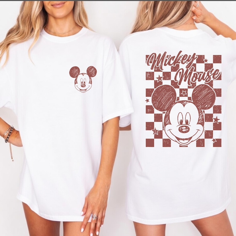 May include: White t-shirts featuring a distressed Mickey Mouse graphic. One shirt has a small Mickey face on the front, while the other displays a larger design on the back with the words "Mickey Mouse" and a checkered pattern.