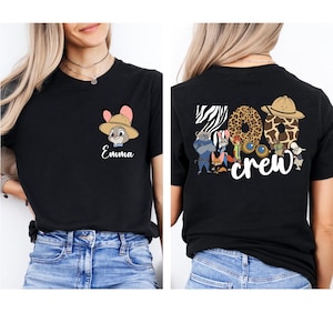 Puede incluir: Camiseta negra con un personaje de dibujos animados con sombrero y el nombre "Emma" en escritura blanca. La parte trasera de la camiseta muestra las palabras "Zoo Crew" con letras de estampado animal y personajes de dibujos animados.