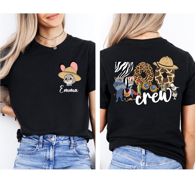 Puede incluir: Camiseta negra con un personaje de dibujos animados con sombrero y el nombre "Emma" en escritura blanca. La parte trasera de la camiseta muestra las palabras "Zoo Crew" con letras de estampado animal y personajes de dibujos animados.