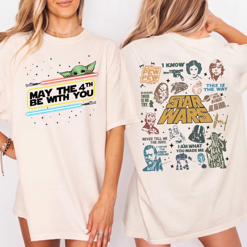 以下が含まれることがあります： スターウォーズのグラフィックが特徴のクリーム色のTシャツ。「May the 4th Be With You」の文字と、ヨーダとライトセーバーが前面にプリントされています。背面には、スターウォーズシリーズの様々なキャラクターと引用句が描かれています。