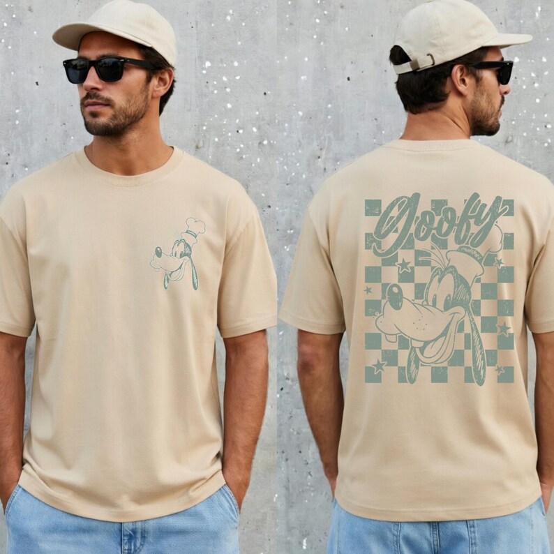 May include: Tan t-shirt featuring a cartoon image of Goofy wearing a chef's hat on the front and back. The back of the shirt has the word "Goofy" above a checkered pattern with stars and another image of Goofy.