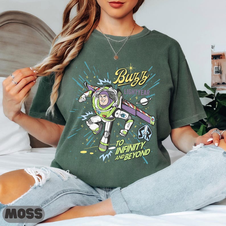 May include: Green t-shirt featuring Buzz Lightyear from Toy Story. The graphic includes Buzz in his spacesuit, the words "Buzz Lightyear" and "To Infinity and Beyond" in a stylized font. The shirt is a solid green color.