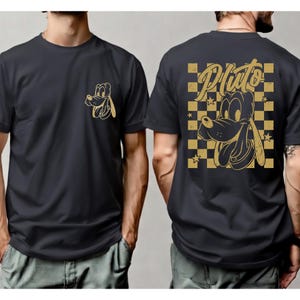 May include: Black t-shirt featuring a gold Pluto graphic on the front and back. The front has a small Pluto head, while the back showcases a larger Pluto design within a gold and black checkered pattern, with the name "Pluto" above the character.