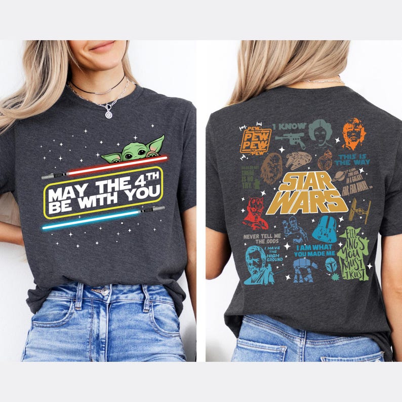 以下が含まれることがあります： スターウォーズをテーマにした濃いグレーのTシャツ。前面には、ライトセーバーとグローグーのグラフィックで「May the 4th Be With You」と表示されています。背面には、さまざまなスターウォーズのキャラクターと引用句が表示されています。
