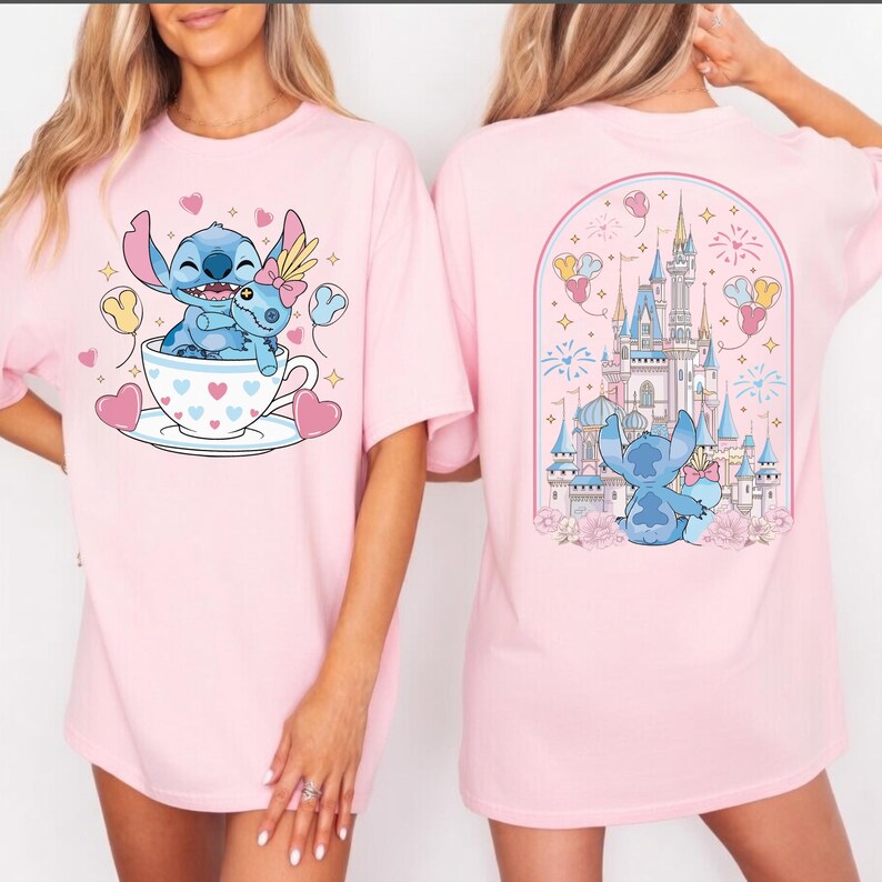 May include: Pink t-shirts featuring a cartoon illustration of Stitch and Angel. The front design shows Stitch and Angel in a teacup, surrounded by hearts and balloons. The back design features Stitch and Angel in front of a castle.