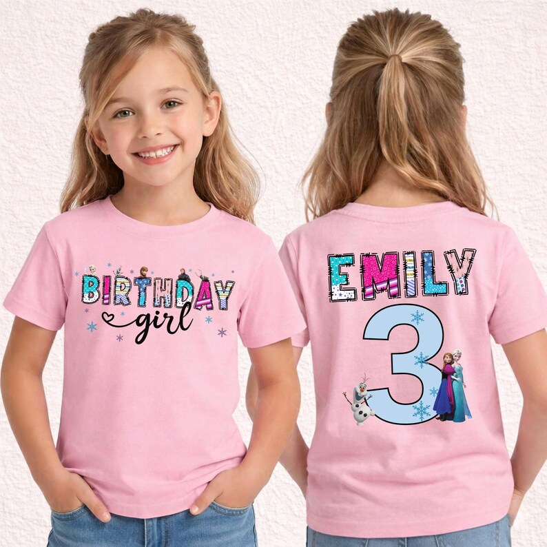 May include: Pink short-sleeved t-shirt with the text "BIRTHDAY girl" in a colorful, glittery font on the front. The back of the shirt features the name "EMILY" and the number "3" with cartoon characters.