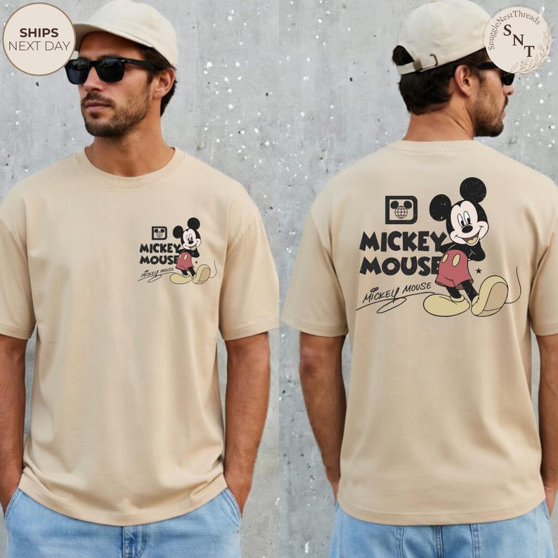 May include: Tan t-shirt featuring Mickey Mouse. The front has a small graphic of Mickey Mouse with the text "Mickey Mouse". The back has a larger Mickey Mouse graphic and the text "Mickey Mouse".
