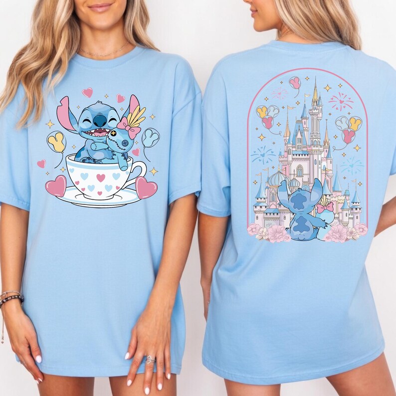May include: Light blue t-shirt featuring a cartoon illustration of Stitch and a smaller Stitch in a teacup with hearts. The back of the shirt shows Stitch in front of a castle with fireworks and balloons.