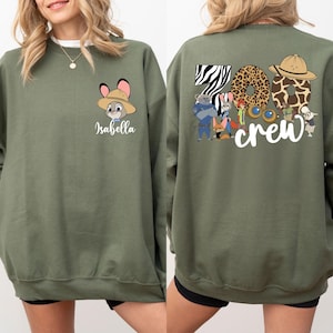 Puede incluir: Sudadera verde oliva con un conejo de dibujos animados con un sombrero de safari y el nombre "Isabella" debajo. La parte trasera muestra "Zoo Crew" con n&uacute;meros con estampado animal y personajes de dibujos animados.
