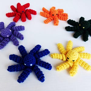 May include: Six crocheted octopus plushies in different colors: red, purple, black, blue, yellow, and orange. Each octopus has eight tentacles and a small, round head with eyes.