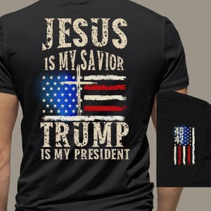 May include: Black t-shirt with the text "Jesus is my savior" and "Trump is my president" with an American flag and a cross in the middle. The shirt also has a small American flag with the numbers 45, 46, and 47 on the sleeve.