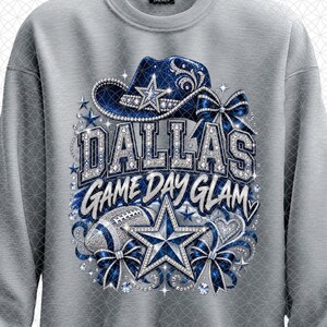 May include: A light gray crewneck sweatshirt featuring a graphic print of a blue cowboy hat, a football, and a large star. The text reads DALLAS GAME DAY GLAM in silver glitter lettering. The design is accented with blue bows and sparkling rhinestones.