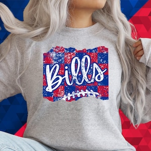 May include: A gray sweatshirt with a distressed red and blue checkered design and the word "Bills" in white lettering. A white football graphic is below the text.