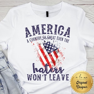 May include: White t-shirt with a distressed American flag graphic. The shirt features the text "AMERICA, A COUNTRY SO GREAT EVEN THE haters WON'T LEAVE" in navy blue. A gold seal with "Original Designer" is in the bottom right.