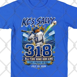 May include: A bright blue t-shirt featuring a graphic of a baseball player swinging a bat. The text reads KC'S SALVY, PEREZ 13, 318, ALL-TIME HOME RUN KING, THE PRIDE OF KC, and JULY 25, 2026. The design includes a gold crown, a stadium, and a baseball.