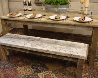 May include: A rustic wooden dining table with a matching bench. The table is set with white plates, napkins, and silverware for four. Champagne flutes and candles add to the ambiance. The table is approximately 72 inches long.