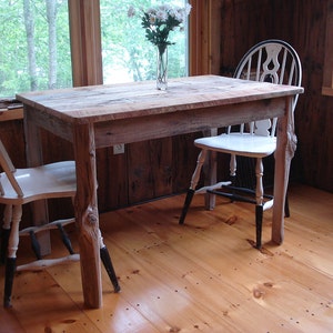 May include: A rustic wooden table with a white painted chair. The table has a natural wood finish and is made from reclaimed wood. The chair has a white painted finish and black legs.