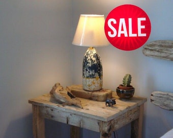 May include: A rustic wooden side table with a lamp, cactus, and decorative items. The lamp has a cream-colored shade and a patterned base. A red circle with the word "SALE" is visible.