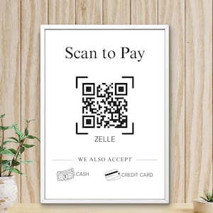 Puede incluir: Un letrero rectangular blanco en un marco delgado con el texto negro Scan to Pay sobre un código QR. Debajo del código está la palabra ZELLE, seguida del texto WE ALSO ACCEPT, con pequeños iconos de línea para efectivo y tarjeta de crédito.