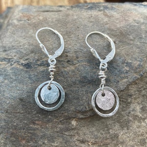 May include: A pair of silver dangle earrings with a hammered circle design. The earrings have a leverback closure.