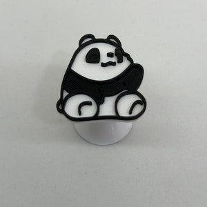 May include: A black and white 3D printed panda bear figurine. The panda is sitting on a white base.