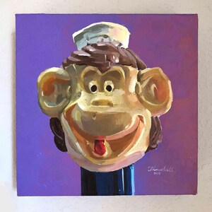 May include: A painting of a monkey wearing a sailor hat. The monkey is smiling and has a red tongue sticking out. The background is purple.