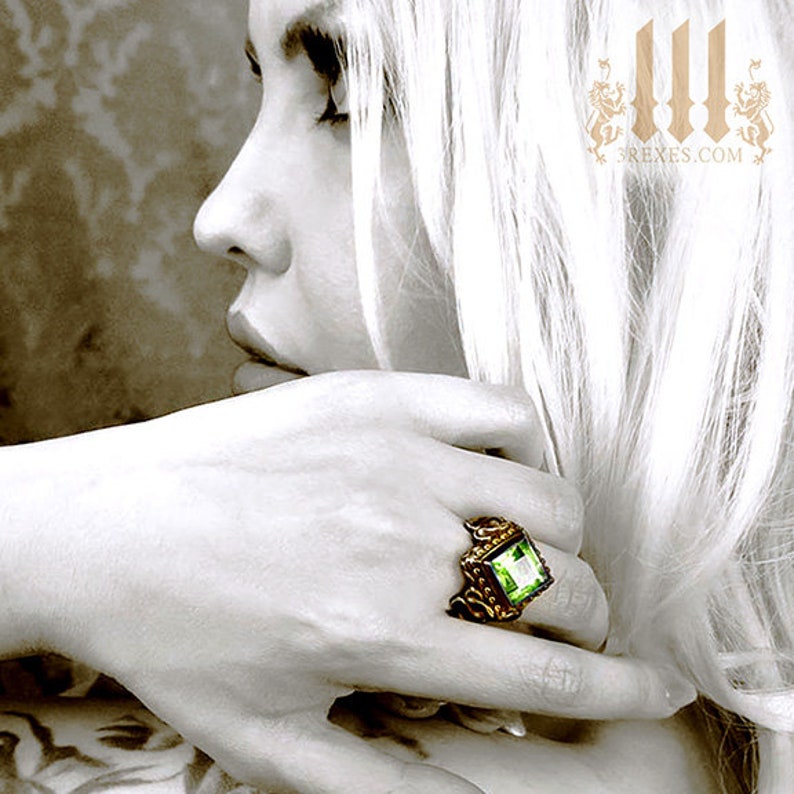 gothic dom model wearing a dark bronze ring with green peridot stone, royal wedding rings with unisex style