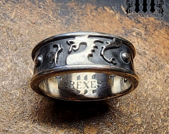 May include: A silver ring with a dragon design on the top and the word "Rexes" engraved on the inside.