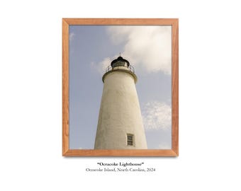 May include: A white lighthouse with a black roof and a black lantern on top. The lighthouse is framed in a wooden frame. The text "Ocracoke Lighthouse" and "Ocracoke Island, North Carolina, 2024" is below the image.
