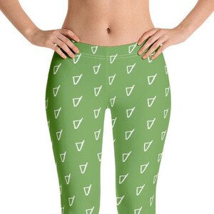 May include: Full-length leggings in a solid grass green color featuring a repeating pattern of small, white, outlined triangle shapes distributed evenly across the fabric. The leggings have a high waistband and a fitted silhouette.