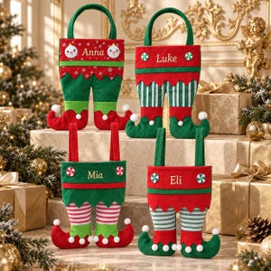 May include: Four felt elf-themed gift bags with handles, each featuring a personalised name: Anna, Luke, Mia, or Eli. The bags are designed to look like elf legs with curled toes, decorated with white pom-poms, stripes, and festive holiday patterns.