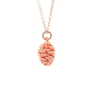 May include: A rose gold necklace featuring a delicate pine cone pendant.