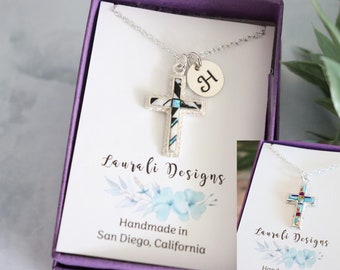 May include: Two silver necklaces with cross pendants in a purple box. The cross pendants are made of turquoise and other stones. The necklaces are from Laura Li Designs and are handmade in San Diego, California.