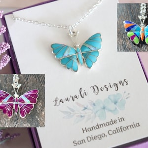 May include: A silver necklace featuring a turquoise butterfly pendant. The image also shows two other butterfly pendants in different colours. The box reads "Laurali Designs Handmade in San Diego, California."