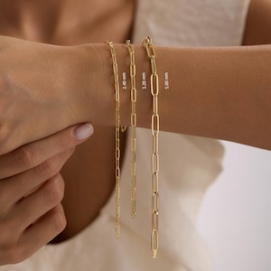 May include: Three gold chain necklaces with varying link sizes are displayed on a person's arm. The chains are 2.40 mm, 3.20 mm, and 5.00 mm in width. The jewelry is gold-colored and appears to be made of metal.
