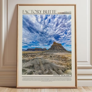 以下が含まれることがあります： ユタ州、アメリカ合衆国のファクトリービュートの風景写真がフレームに入っています。ドラマチックな空と、起伏のある砂漠地帯が写っています。場所の名前と座標が記載されています。