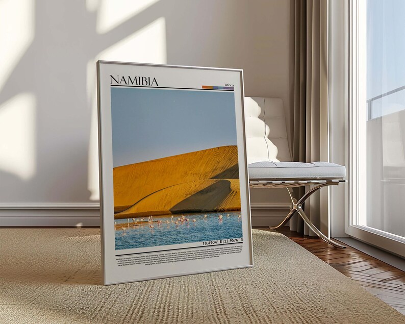 May include: A framed print featuring a landscape of Namibia. The image shows a golden sand dune, a body of water with pink flamingos, and a blue sky. The word "NAMIBIA" is printed at the top of the frame.