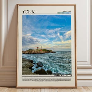 May include: Framed print featuring a coastal scene with a lighthouse on a rocky island under a blue and cloudy sky. The word "York" is at the top, with "Maine, USA" below it. Coordinates are at the bottom.