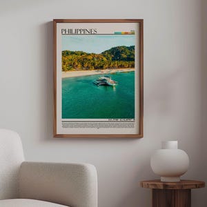 May include: A framed print of the Philippines, showcasing a tropical beach scene with turquoise water, white sand, and lush green hills. The print includes the word "PHILIPPINES" at the top and coordinates at the bottom. The frame is a warm brown.