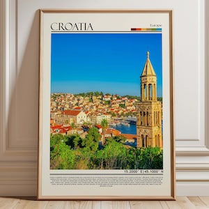 May include: Framed travel poster featuring the word "Croatia" at the top, with a scenic view of a coastal town under a clear blue sky. The image includes a tall stone tower and a harbor filled with boats. The poster has a beige border.