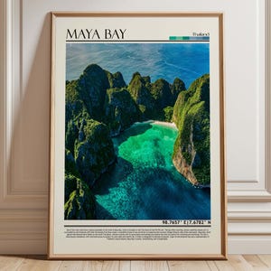 May include: Framed print of Maya Bay, Thailand, featuring a vibrant aerial view of turquoise waters and lush green cliffs. The print includes the text "MAYA BAY" at the top and coordinates at the bottom. The frame is a light brown color.